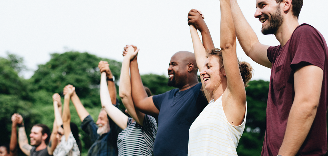 Group of people holding their hands up in the air together during a team bonding activity