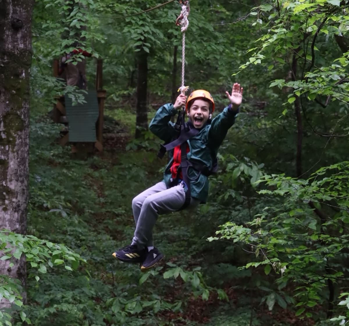 Young zipliner in a helmet and harness soaring through the forest on the Express Zip at Fontanel